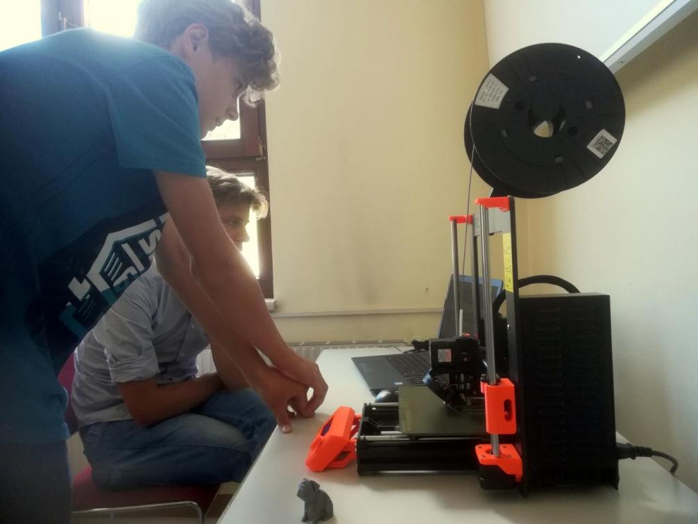 Schüler und Lehrer beim Bedienen eines 3D-Druckers